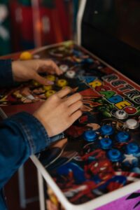 Primer plano de unas manos usando una máquina arcade con múltiples botones de colores y joystick.