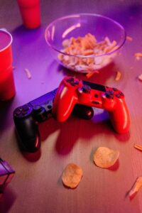 Dos mandos de videojuegos (uno rojo y uno negro) sobre una mesa iluminada con luz roja